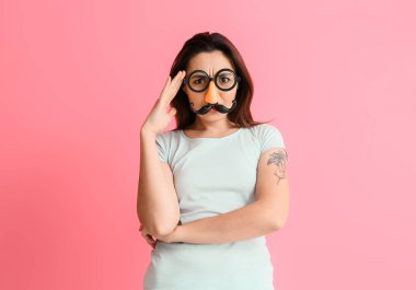 Pembe arka planda komik kılık değiştirmiş genç bir kadın. 1 Nisan kutlamaları