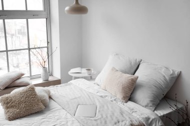 Yatağın yanındaki beyaz duvarın yanındaki modern dizüstü bilgisayar.