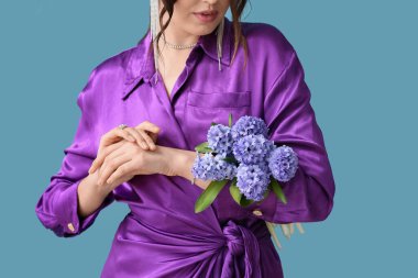 Mavi arka planda sümbül çiçekleri olan güzel genç bir kadın.