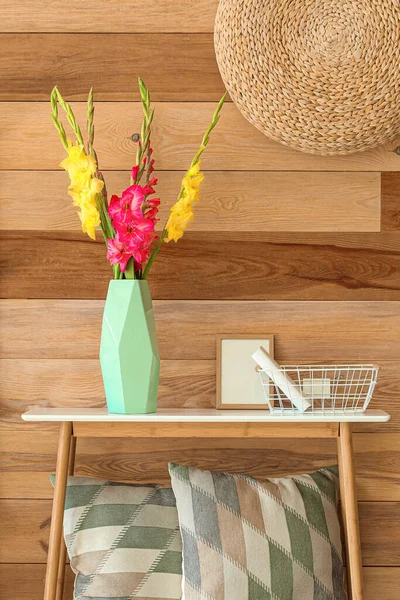 Güzel gladiolus çiçekli vazo, sepet ve ahşap duvarın yanındaki boş çerçeve.