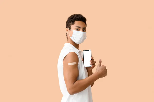 戴口罩的年轻非洲裔美国人 带着医疗补丁和手机 在米色背景下大显身手 — 图库照片
