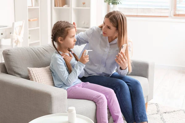 小女孩提着喉头酸痛喷出的喷雾和她妈妈在家里和医生聊天的视频 — 图库照片