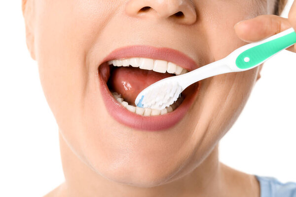 Красивая зрелая женщина чистит зубы на белом фоне, крупным планом