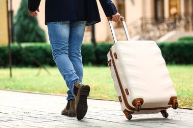 Bavullu genç adam dışarıda yürüyor.