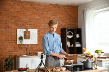 Genç adam mutfakta video dersi izlerken mantarlı pilav pişiriyor.