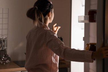 Geceleri açık buzdolabının yanında genç bir kadın.