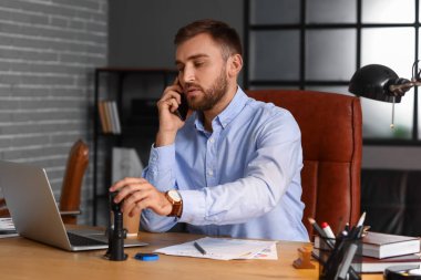 Erkek noter ofiste telefonla konuşuyor.