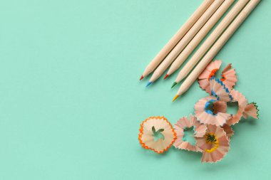 Turkuaz arka planda renkli kalemler ve talaşlar