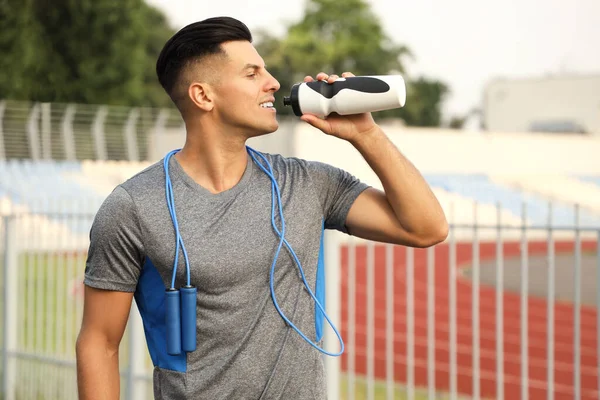 Sporty Young Man Skipping Rope Drinking Water Outdoors — Stock Photo, Image