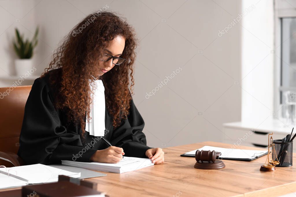 Female judge signing documents at workplace in courtroom
