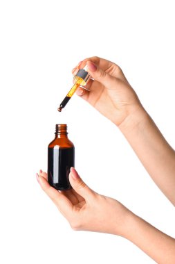 Beyaz arka planda şişe ve iyot pipetli kadın elleri.