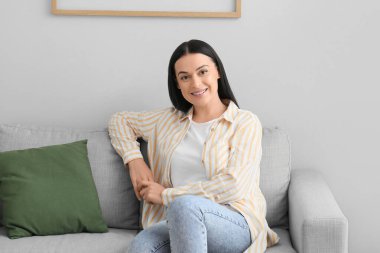 Diş teli takan güzel bir kadın evdeki kanepede oturuyor.