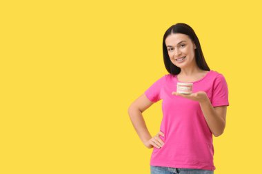 Diş telleri ve sarı arka planda çene modeli olan güzel bir kadın.