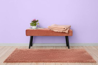 Çiçekli tencere, dergiler ve menekşe duvarın yanındaki bankta ekose.