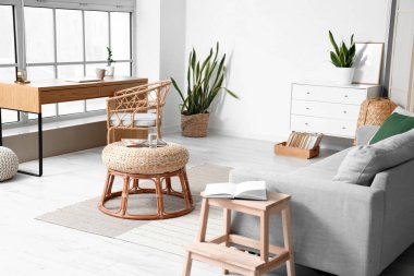 Aydınlık oturma odasında bir bardak su ve dergi olan şık bir masa.