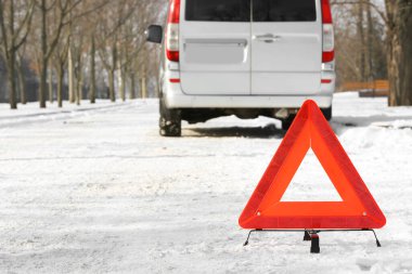 Karlı kış gününde acil durum levhası ve bozuk araba.