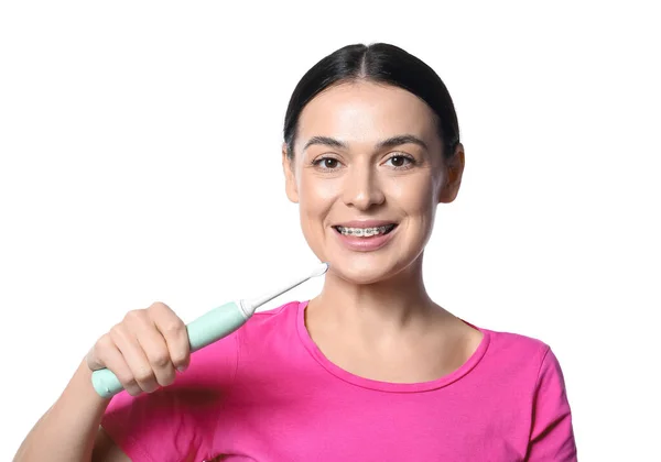 白い背景に歯科用ブレースと電動歯ブラシを持つ美しい女性 — ストック写真