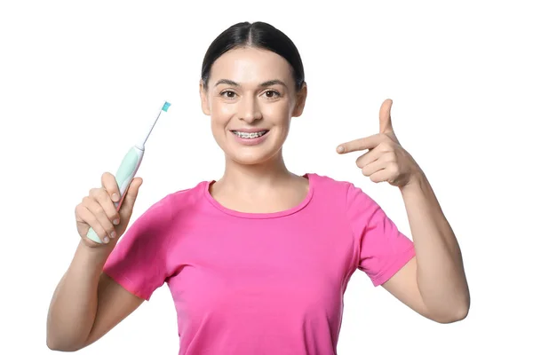 Красива Жінка Зубними Дужками Вказують Електричну Зубну Щітку Білому Тлі — стокове фото