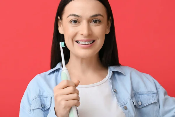 Красива Жінка Зубними Брекетами Електричною Зубною Щіткою Червоному Тлі — стокове фото