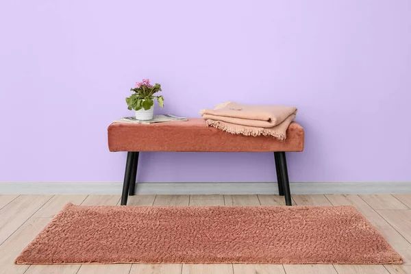 Çiçekli tencere, dergiler ve menekşe duvarın yanındaki bankta ekose.