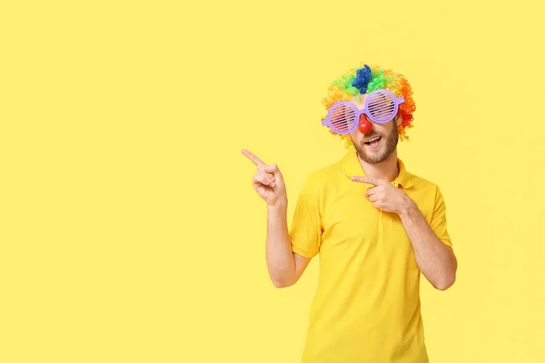 一个伪装得很有趣的年轻人在黄色背景上展示了一些东西 四月愚人节庆祝活动 — 图库照片