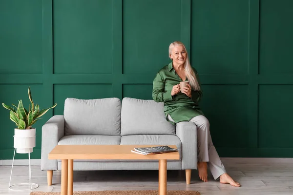 Mature Woman Drinking Tea While Sitting Sofa Green Wall — Stock Photo, Image