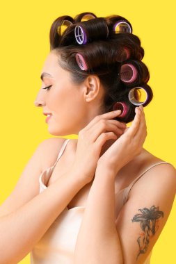 Sarı arka planda saç lastiği takan güzel genç bir kadın.