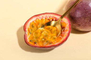 Sarı arka planda lezzetli tutku meyveleri olan kaşık.