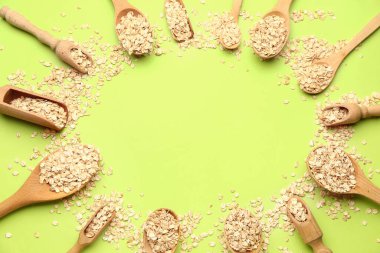 Yeşil arka planda çiğ yulaf ezmesi ve kaşıklardan yapılmış çerçeve