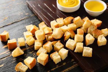 Koyu ahşap arka planda lezzetli kıtır ekmekler ve soslu pano, yakın plan.