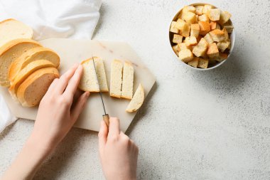Beyaz arka planda kızarmış ekmek için taze ekmek kesen kadın.