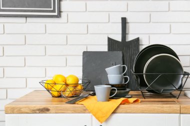 Beyaz tuğla duvarın yanında limonlu modern yemek takımı ve kase.