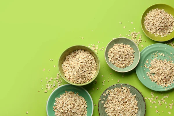 Yeşil arka planda çiğ yulaf ezmesi tabakları ve kaseler