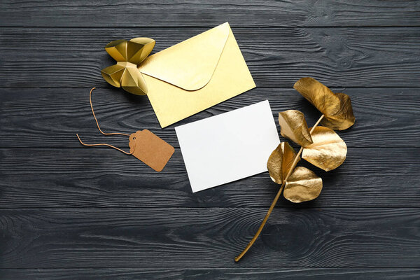 Envelope with blank card, tag and decor on dark wooden background