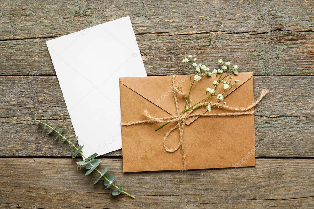 Envelope with card, flowers and eucalyptus branch on dark wooden background