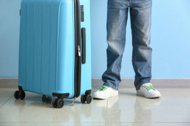 Mavi duvarın yanında bavulu olan sevimli küçük çocuk.