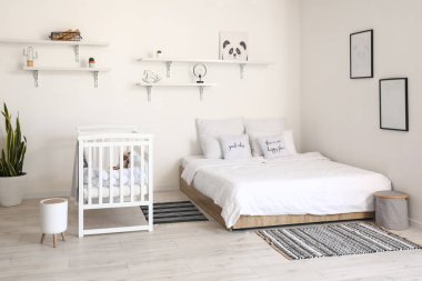 Büyük yataklı, rahat bebek karyolası olan rahat bir odanın modern iç mekanı.