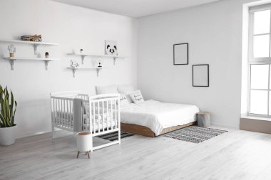 Büyük yataklı, rahat bebek karyolası olan rahat bir odanın modern iç mekanı.