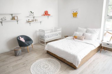 Büyük yataklı, rahat bebek karyolası olan rahat bir odanın modern iç mekanı.