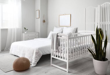 Büyük yataklı, rahat bebek karyolası olan rahat bir odanın modern iç mekanı.