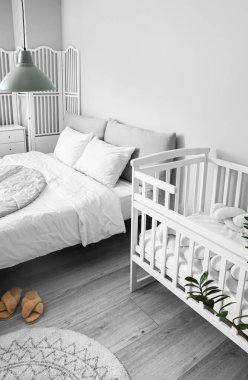 Büyük yataklı, rahat bebek karyolası olan rahat bir odanın modern iç mekanı.