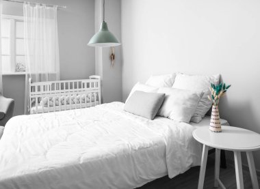 Büyük yataklı, rahat bebek karyolası olan rahat bir odanın modern iç mekanı.