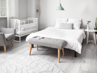 Büyük yataklı, rahat bebek karyolası olan rahat bir odanın modern iç mekanı.