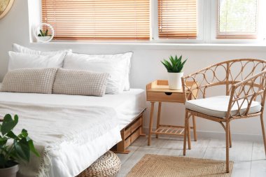 Şık bir odada yatağın yanında rahat bir sandalye.