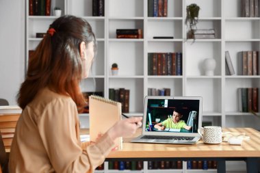 Not defteriyle evde ders veren Asyalı bir öğretmen.