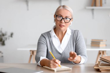 Bayan öğretmen evde ders veriyor.