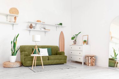 Tahta sörf tahtası, kanepesi ve bitkileriyle aydınlık oturma odasının içinde.