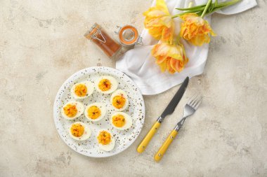 Doldurulmuş yumurta, çiçek, çatal bıçak ve baharatlı tabak. Paskalya kutlaması