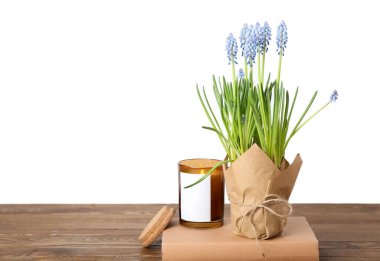 Çiçek açan üzüm sümbülü (Muscari), masa üzerinde beyaz arka plan karşı kitap ve mum