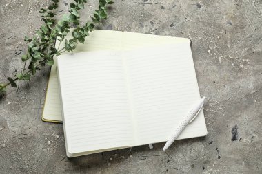 Grunge arkaplanındaki not defterleri, kalem ve yeşil şubeler